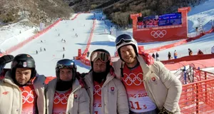 Štyria ľudia v bundách slovenskej olympijskej výpravy pod zjazdovkou v Pekingu 2022.