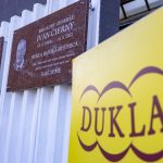 pamätná tabuľa I. Čierneho na stene v zábere s rollupom VŠC DUKLA